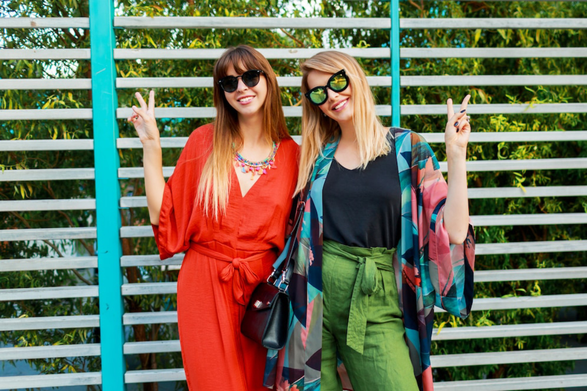 Two women pose playfully, one in a red dress and the other in a patterned kimono.
