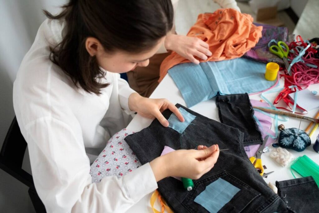 A person sewing a patch onto black fabric