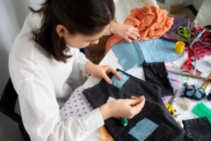 A person sewing a patch onto black fabric