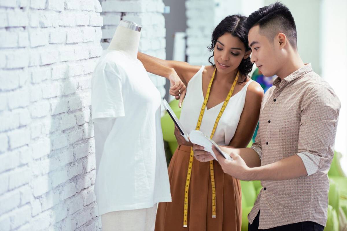 A woman adjusts a white shirt on a mannequin