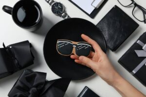 A hand holds a sunglasses-shaped cookie above a black plate