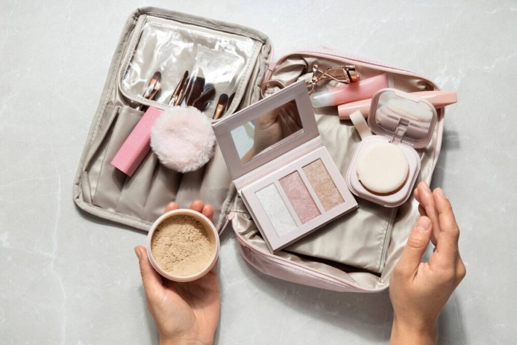 Flat lay of beauty products and accessories on a vibrant yellow background, featuring a notebook, makeup brushes, perfume, and jewelry.